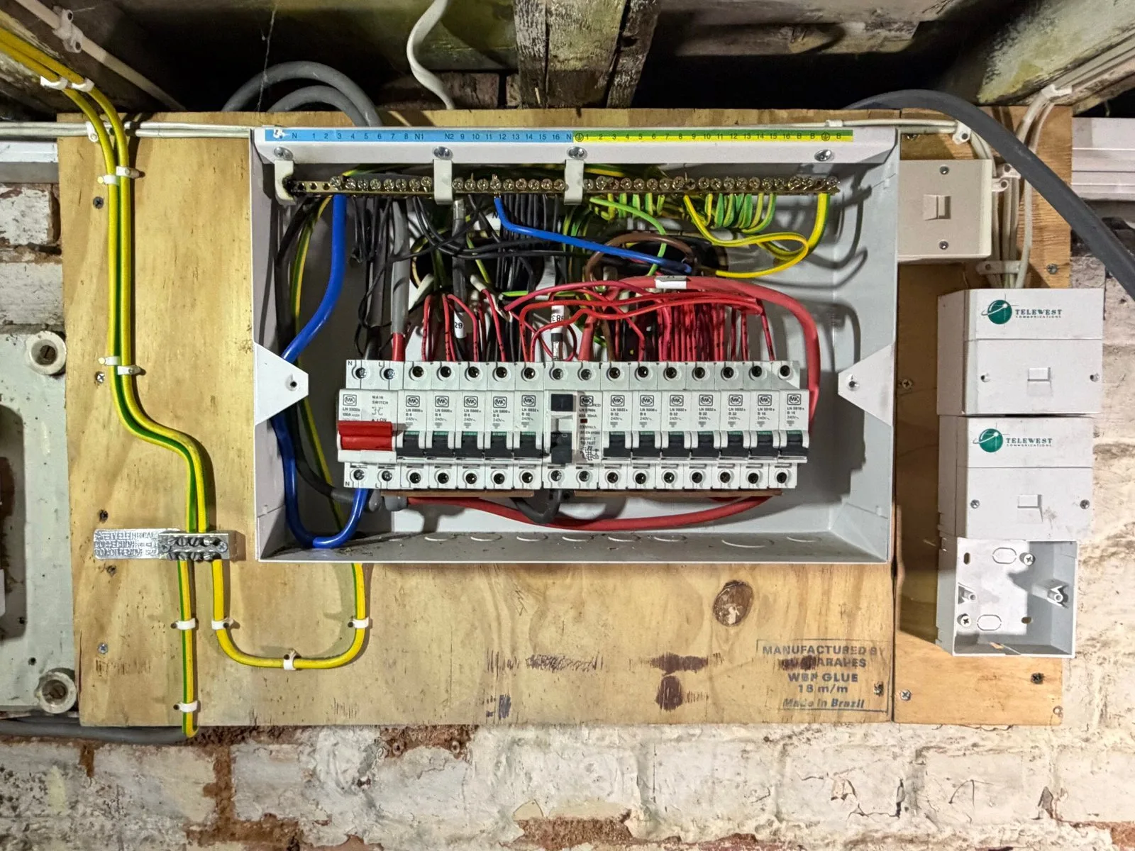 16-way MK consumer unit in Muswell Hill N10 with messy red switched-live cabling above the board — half the circuits without RCD protection