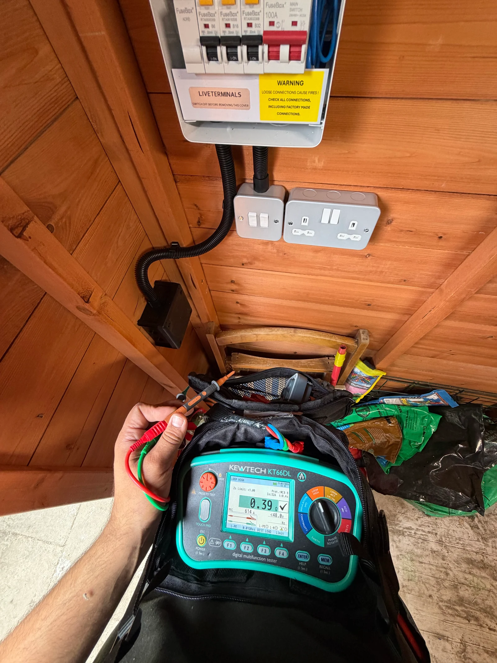 Kewtech multifunction tester in use beside a consumer unit