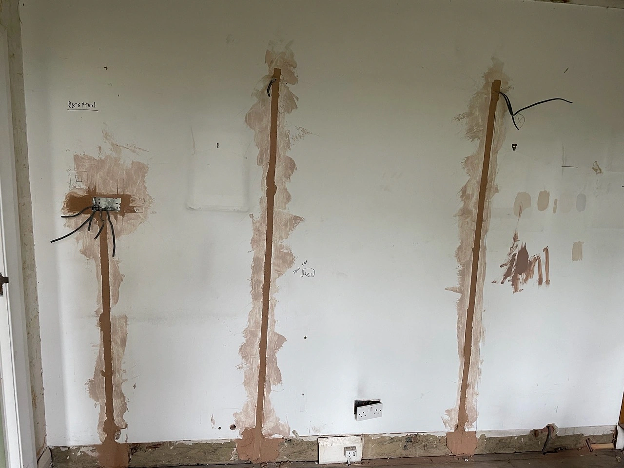Multiple electrical wall chases filled with plaster during a North London house rewire