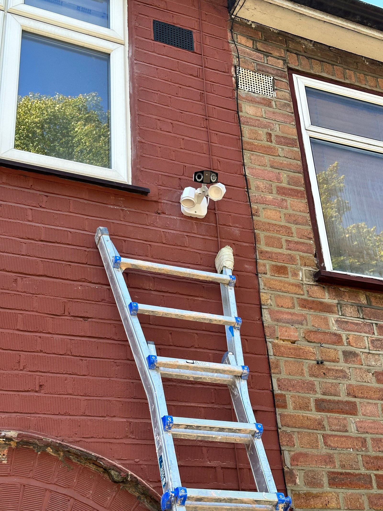 Reolink floodlight camera high on brick wall — North London