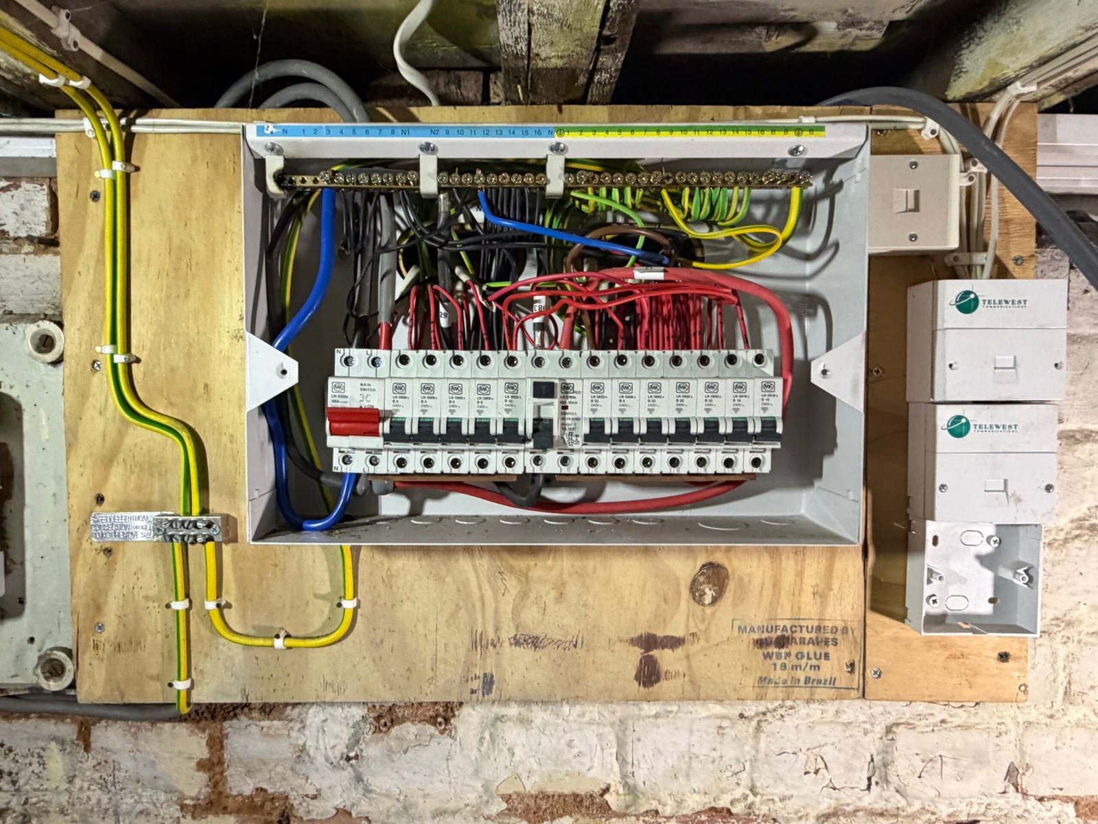 16-way MK consumer unit in Muswell Hill N10 with messy red switched-live cabling above the board — half the circuits without RCD protection
